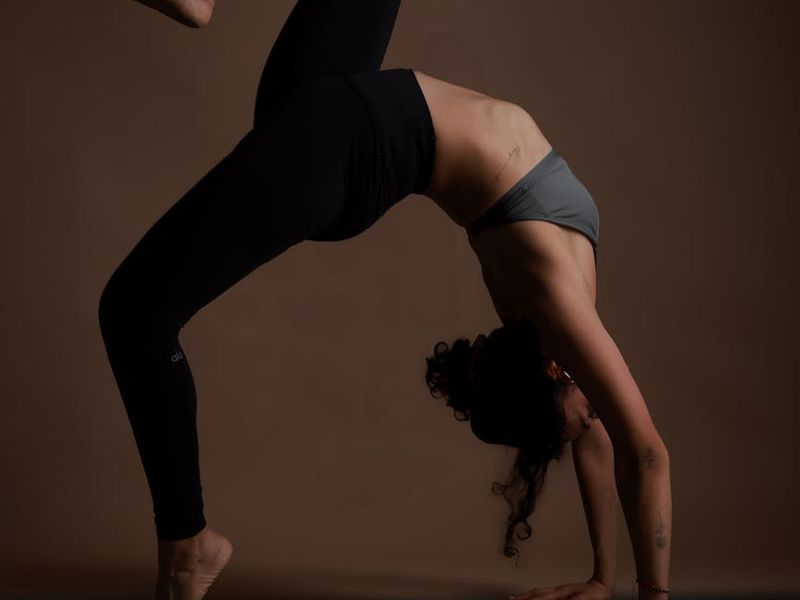 Person practicing yoga in a dark minimalist studio environment.